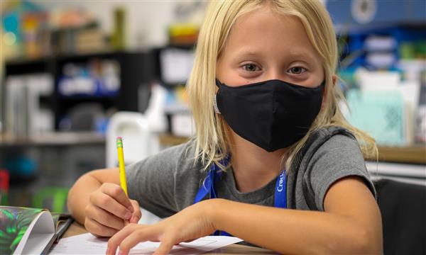 student smiles at camera while sitting at desk